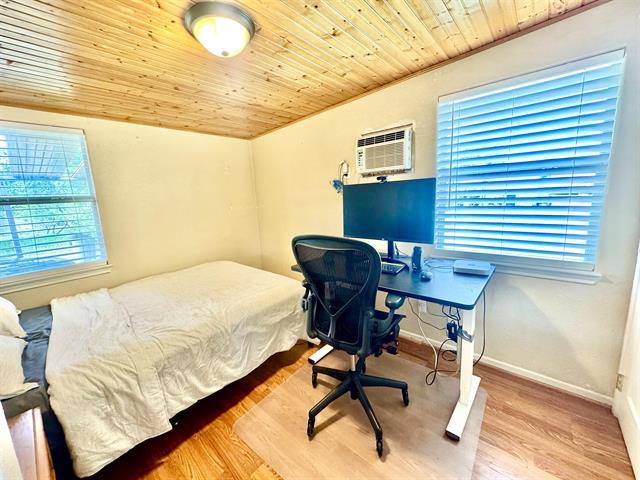 1415 Bee Ln, Tow, TX 78672 - bedroom featuring wooden ceiling, wood finished floors, a wall unit AC, baseboards, and an office area