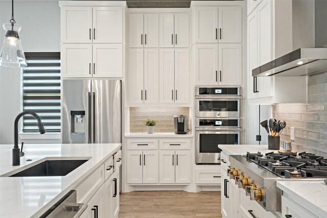 335 Sandy Mountain Dr, Sunrise Beach, TX 78643 - kitchen with wall chimney exhaust hood, stainless steel appliances, a sink, white cabinetry, and tasteful backsplash