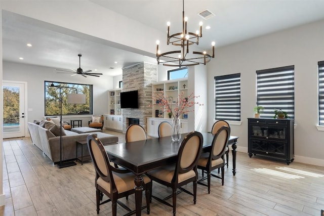 335 Sandy Mountain Dr, Sunrise Beach, TX 78643 - dining room featuring healthy amount of natural light, a large fireplace, light wood finished floors, a chandelier, and recessed lighting