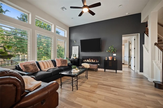 5820 Harper Park Dr Unit 66, Austin, TX 78735 - living room with a ceiling fan, stairs, light wood-style floors, a lit fireplace, and recessed lighting