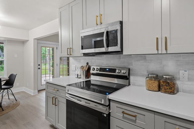 13322 Villa Park Dr, Austin, TX 78729 - kitchen featuring appliances with stainless steel finishes, gray cabinetry, healthy amount of natural light, and light countertops