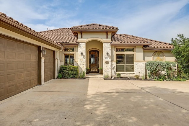 17400 Northlake Hills Dr, Jonestown, TX 78645 - mediterranean / spanish home featuring concrete driveway, a garage, a tile roof, stucco siding, and stone siding