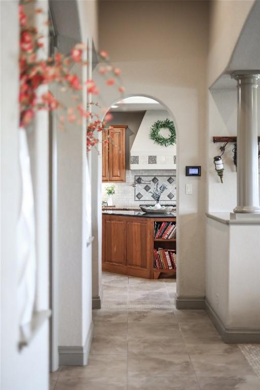 17400 Northlake Hills Dr, Jonestown, TX 78645 - kitchen featuring brown cabinets, backsplash, arched walkways, light countertops, and baseboards