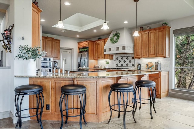 17400 Northlake Hills Dr, Jonestown, TX 78645 - kitchen featuring premium range hood, stainless steel refrigerator with ice dispenser, a peninsula, backsplash, and light stone counters