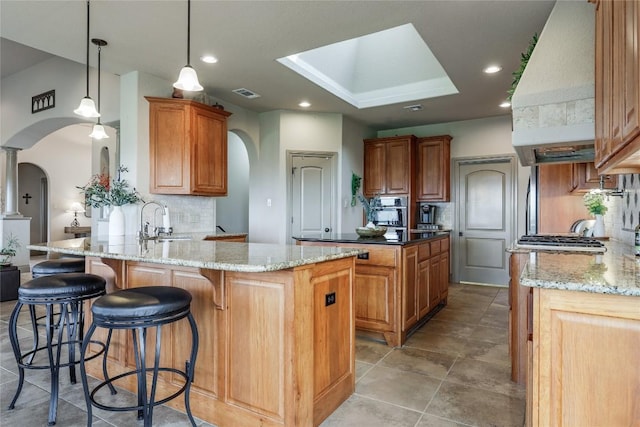 17400 Northlake Hills Dr, Jonestown, TX 78645 - kitchen featuring arched walkways, custom range hood, a sink, tasteful backsplash, and recessed lighting