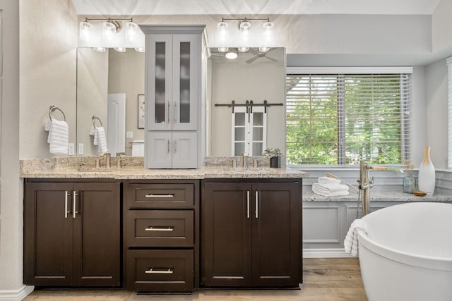 3808 Royal Troon Dr, Round Rock, TX 78664 - bathroom with double vanity, a soaking tub, and wood finished floors