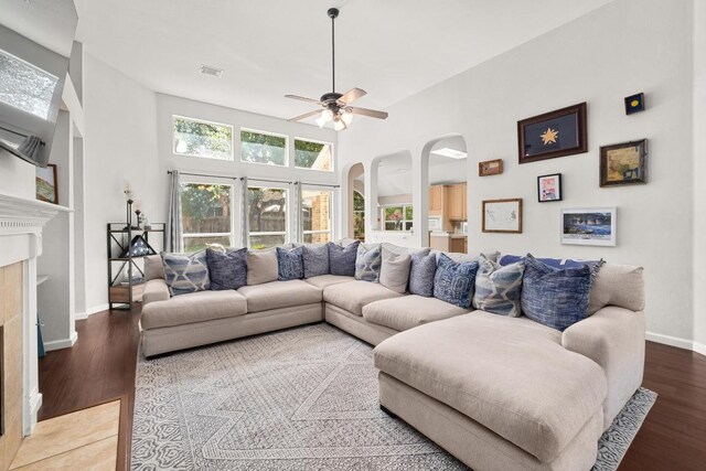 10609 Thoroughbred Dr, Austin, TX 78748 - living room featuring arched walkways, wood finished floors, a fireplace with flush hearth, a ceiling fan, and a towering ceiling