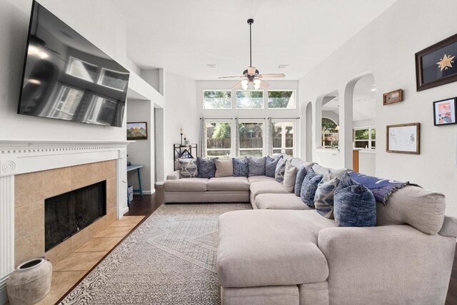 10609 Thoroughbred Dr, Austin, TX 78748 - living area with a ceiling fan, a tiled fireplace, wood finished floors, arched walkways, and a towering ceiling