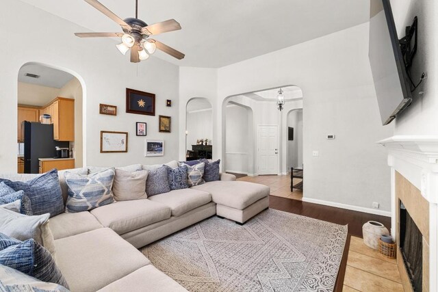 10609 Thoroughbred Dr, Austin, TX 78748 - living room with arched walkways, a ceiling fan, a fireplace, light wood-style floors, and baseboards