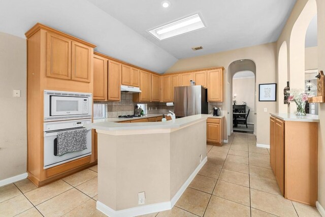10609 Thoroughbred Dr, Austin, TX 78748 - kitchen featuring white appliances, under cabinet range hood, vaulted ceiling, backsplash, and arched walkways