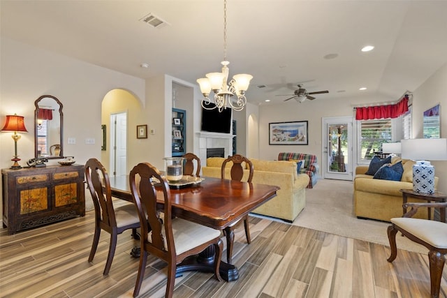 1049 Naranjo Dr, Georgetown, TX 78628 - dining area featuring arched walkways, light wood finished floors, a ceiling fan, a tiled fireplace, and recessed lighting