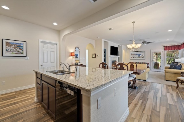 1049 Naranjo Dr, Georgetown, TX 78628 - kitchen with a sink, dishwasher, arched walkways, open floor plan, and light wood finished floors