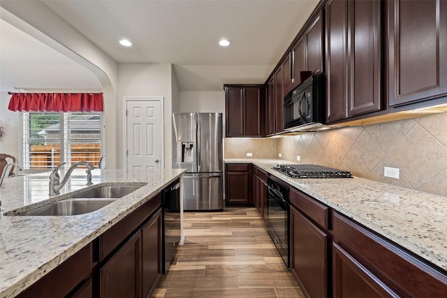 1049 Naranjo Dr, Georgetown, TX 78628 - kitchen with black appliances, a sink, recessed lighting, light wood-style floors, and light stone countertops