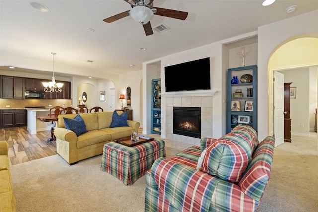 1049 Naranjo Dr, Georgetown, TX 78628 - living area featuring arched walkways, recessed lighting, ceiling fan, a tile fireplace, and a chandelier