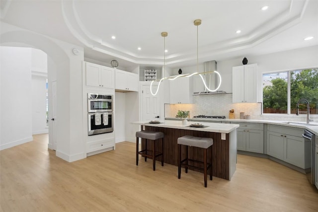 14904 Cordero Dr, Austin, TX 78717 - kitchen featuring a raised ceiling, wall chimney range hood, a sink, decorative backsplash, and light wood-style floors