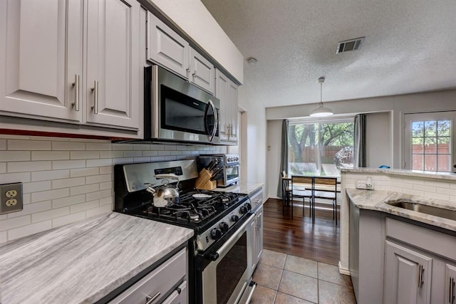 1600 Hatch Rd, Cedar Park, TX 78613 - kitchen with stainless steel appliances, backsplash, a textured ceiling, light stone countertops, and tile patterned floors