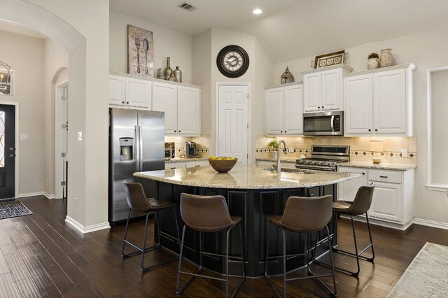 116 Belford St, Georgetown, TX 78628 - kitchen with stainless steel appliances, arched walkways, a sink, white cabinets, and vaulted ceiling