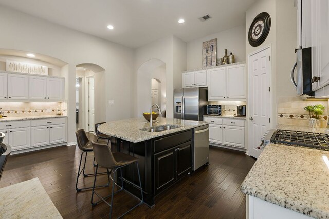 116 Belford St, Georgetown, TX 78628 - kitchen featuring a sink, appliances with stainless steel finishes, tasteful backsplash, arched walkways, and white cabinetry