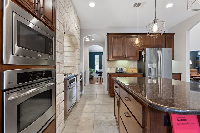 370 Ledge Stone Dr, Austin, TX 78737 - kitchen with stainless steel appliances, arched walkways, decorative backsplash, dark stone counters, and recessed lighting