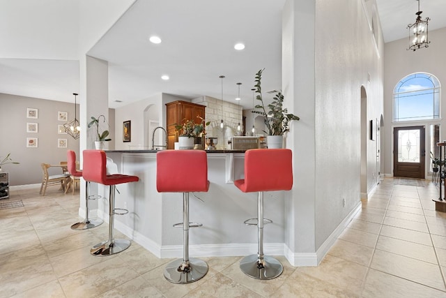 370 Ledge Stone Dr, Austin, TX 78737 - kitchen featuring arched walkways, a breakfast bar, a chandelier, brown cabinets, and recessed lighting