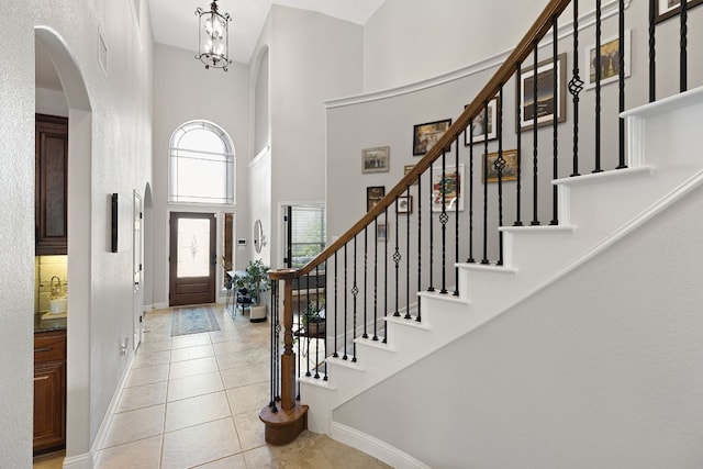 370 Ledge Stone Dr, Austin, TX 78737 - entryway with a high ceiling, arched walkways, baseboards, light tile patterned flooring, and stairs