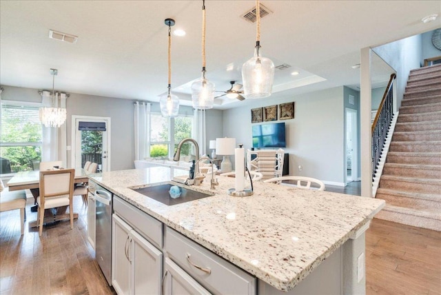 610 Ridge Park Dr, New Braunfels, TX 78130 - kitchen featuring a sink, a kitchen island with sink, light wood-style flooring, light stone counters, and pendant lighting