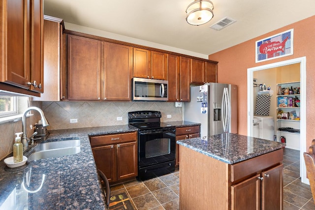 326 Comal Run, Hutto, TX 78634 - kitchen featuring appliances with stainless steel finishes, washer and dryer, backsplash, and dark stone counters