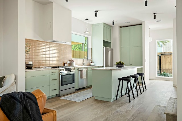 2405 E 22nd St, Austin, TX 78722 - kitchen with green cabinets, appliances with stainless steel finishes, light wood-type flooring, backsplash, and a breakfast bar area