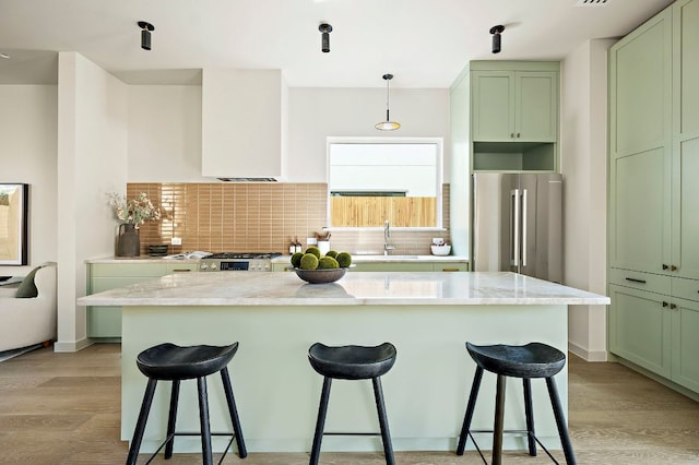 2405 E 22nd St, Austin, TX 78722 - kitchen with high end fridge, green cabinetry, light wood-type flooring, and backsplash