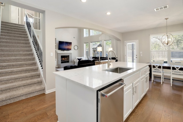 7221 Seneca Falls Loop, Austin, TX 78739 - kitchen featuring stainless steel dishwasher, a sink, a warm lit fireplace, recessed lighting, and hardwood / wood-style floors
