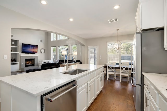 7221 Seneca Falls Loop, Austin, TX 78739 - kitchen featuring stainless steel appliances, a sink, a brick fireplace, open floor plan, and arched walkways