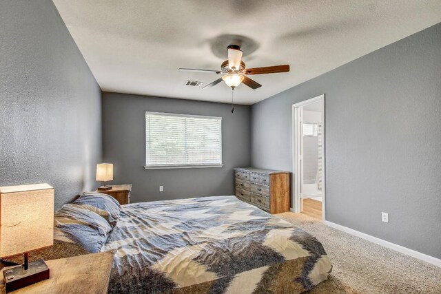 1032 Stacias Way, Pflugerville, TX 78660 - carpeted bedroom featuring baseboards, a textured wall, a ceiling fan, and ensuite bathroom
