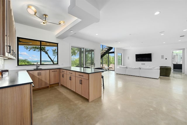 806 Sunfish St, Lakeway, TX 78734 - kitchen with concrete floors, light brown cabinets, a peninsula, recessed lighting, and dark countertops