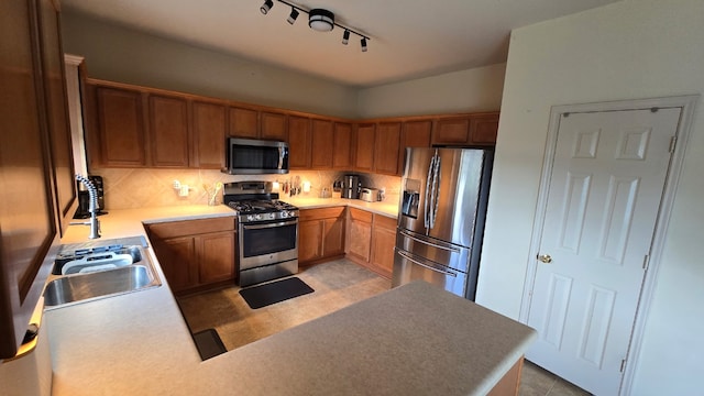 14501 Dreamtime Ln, Pflugerville, TX 78660 - kitchen with stainless steel appliances, tasteful backsplash, track lighting, a sink, and brown cabinetry