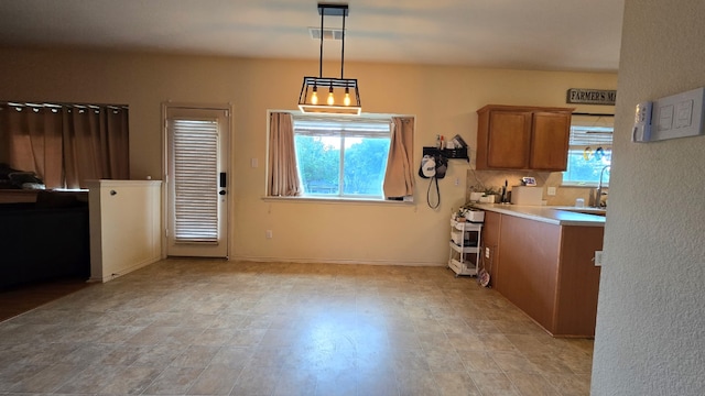 14501 Dreamtime Ln, Pflugerville, TX 78660 - kitchen featuring brown cabinets, pendant lighting, light countertops, and a sink