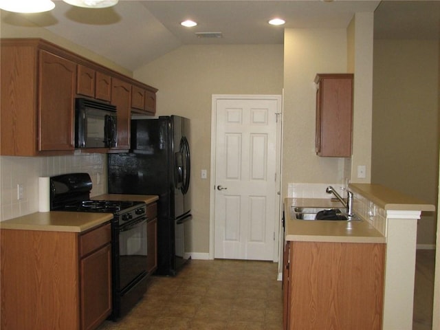 123 Bayliss St, Hutto, TX 78634 - kitchen featuring black appliances, a sink, backsplash, vaulted ceiling, and a peninsula