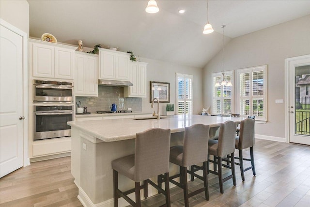 3221 Venezia Vw, Leander, TX 78641 - kitchen featuring light wood-type flooring, light countertops, backsplash, double oven, and a breakfast bar