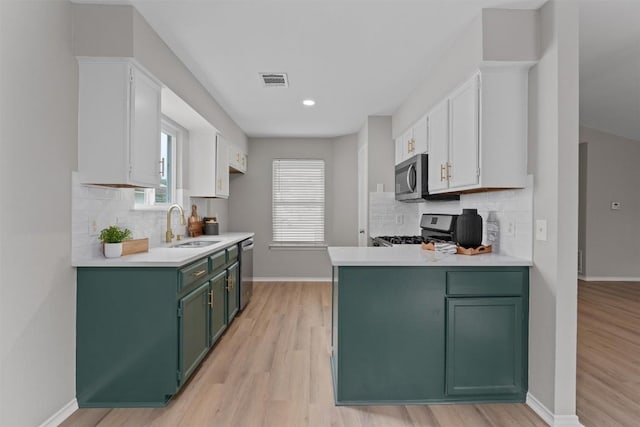 5902 Shreveport Dr, Austin, TX 78727 - kitchen with green cabinetry, stainless steel appliances, a sink, white cabinetry, and light countertops