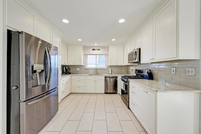 3310 Monument Dr, Round Rock, TX 78681 - kitchen with stainless steel appliances, decorative backsplash, light tile patterned floors, white cabinetry, and light stone countertops