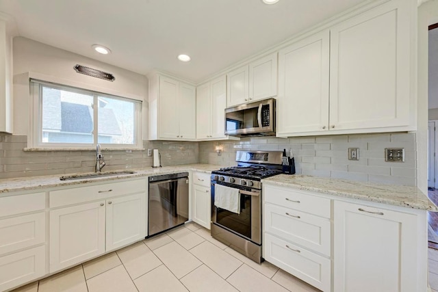 3310 Monument Dr, Round Rock, TX 78681 - kitchen with appliances with stainless steel finishes, light tile patterned floors, white cabinets, backsplash, and light stone counters
