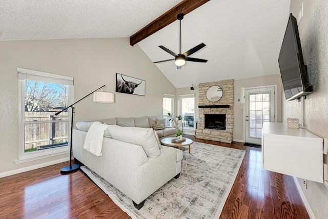 3310 Monument Dr, Round Rock, TX 78681 - living area with a ceiling fan, dark wood-type flooring, beam ceiling, a stone fireplace, and baseboards