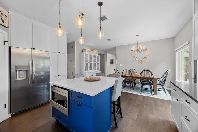 2003 Red Oak Cir, Round Rock, TX 78681 - kitchen with stainless steel appliances, blue cabinetry, dark wood finished floors, a chandelier, and white cabinetry