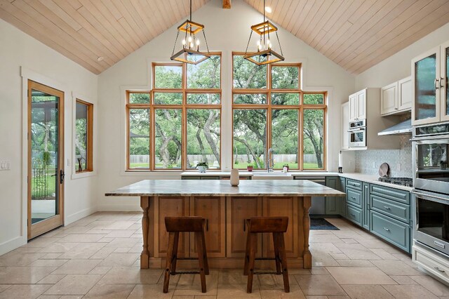2819 Cross Rd, San Marcos, TX 78666 - kitchen with light countertops, a center island, appliances with stainless steel finishes, high vaulted ceiling, and stone tile flooring