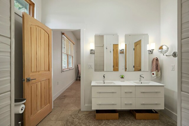 2819 Cross Rd, San Marcos, TX 78666 - bathroom with baseboards, double vanity, and stone finish flooring