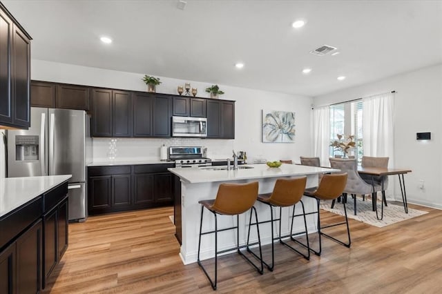 8103 Mandela Bnd, Austin, TX 78744 - kitchen with stainless steel appliances, a sink, light wood finished floors, a kitchen bar, and light countertops