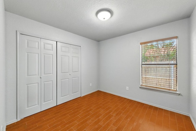 5504 Alomar Cv, Del Valle, TX 78617 - unfurnished bedroom with a closet, a textured ceiling, wood finished floors, and baseboards