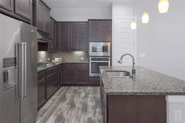 204 Hopping Peach St, San Marcos, TX 78666 - kitchen with appliances with stainless steel finishes, a sink, wood finished floors, stone counters, and backsplash