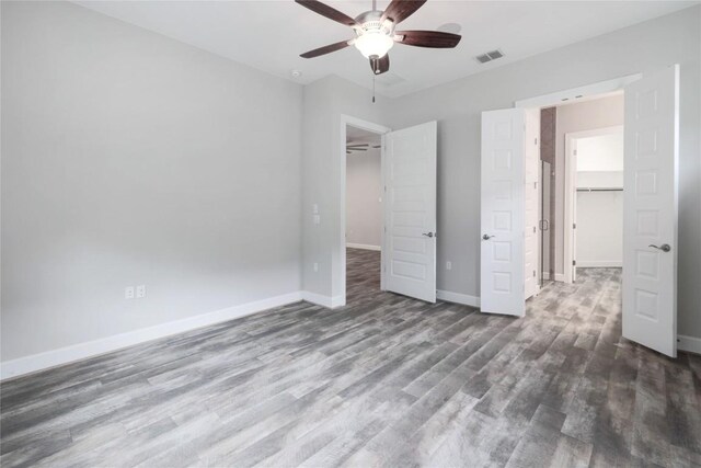 204 Hopping Peach St, San Marcos, TX 78666 - unfurnished bedroom featuring a walk in closet, wood finished floors, baseboards, a closet, and a ceiling fan