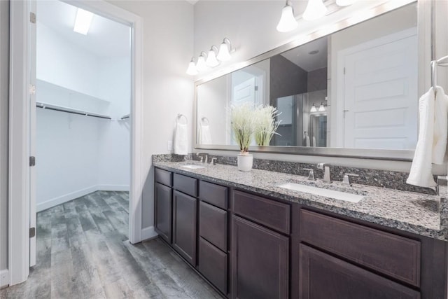 204 Hopping Peach St, San Marcos, TX 78666 - bathroom featuring double vanity, wood finished floors, a spacious closet, and baseboards