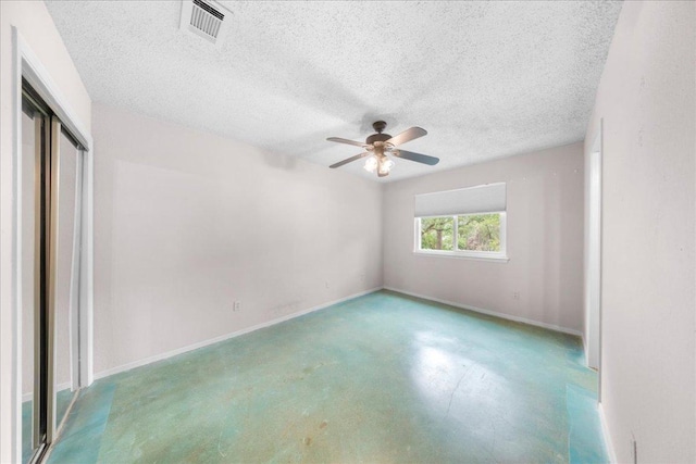 1015 E Yager Ln Unit 187, Austin, TX 78753 - unfurnished bedroom featuring a closet, baseboards, a textured ceiling, a ceiling fan, and concrete floors